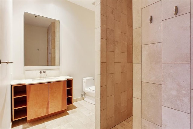 bathroom featuring toilet, vanity, and a tile shower
