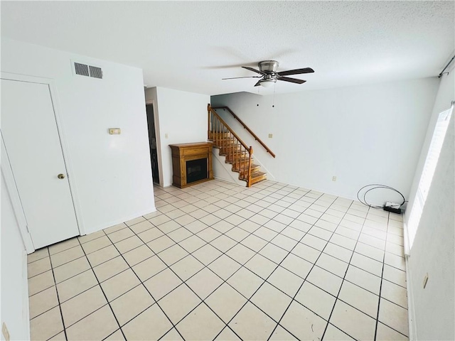 unfurnished living room featuring ceiling fan, a textured ceiling, and light tile patterned floors