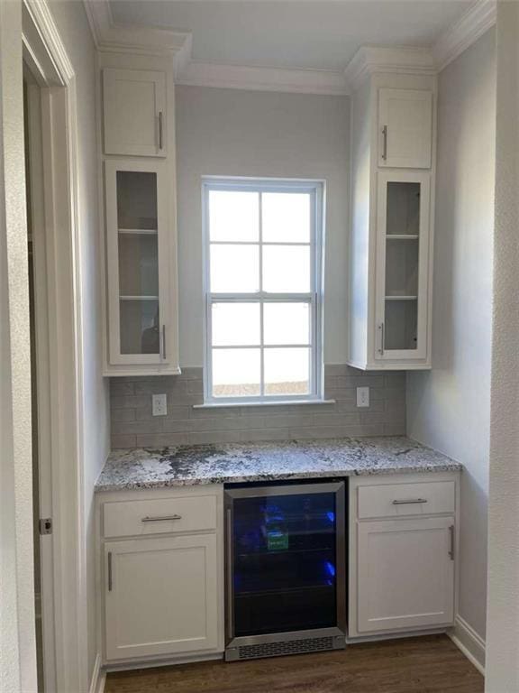 bar featuring wine cooler, light stone counters, and white cabinetry