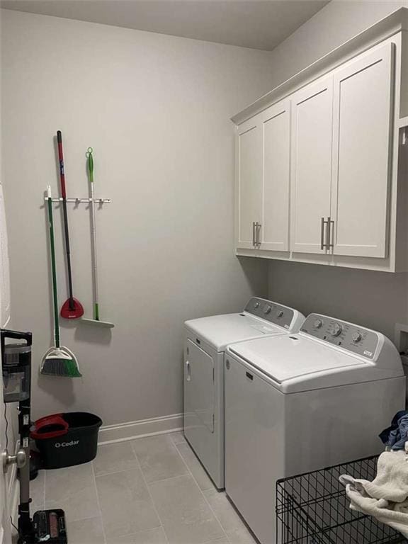 washroom with light tile patterned flooring, cabinets, and washer and clothes dryer