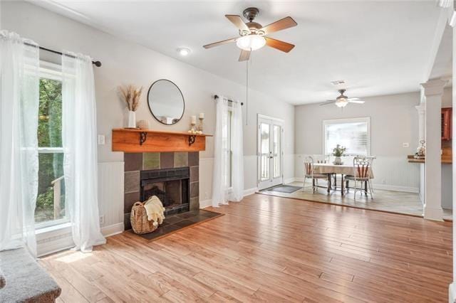 living room with a tiled fireplace, wood-type flooring, and ceiling fan