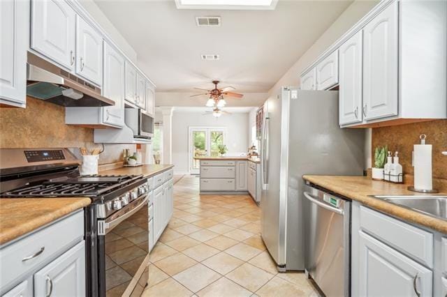 kitchen featuring white cabinetry, light tile patterned floors, appliances with stainless steel finishes, ceiling fan, and decorative backsplash