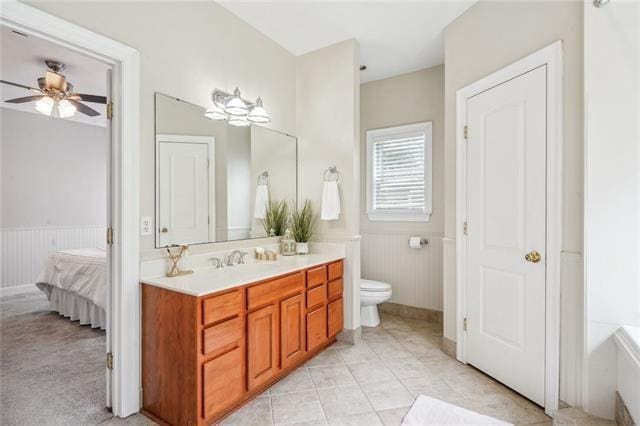 bathroom with a tub to relax in, toilet, vanity, ceiling fan, and tile patterned flooring