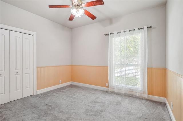 unfurnished bedroom with a closet, ceiling fan, and wood walls