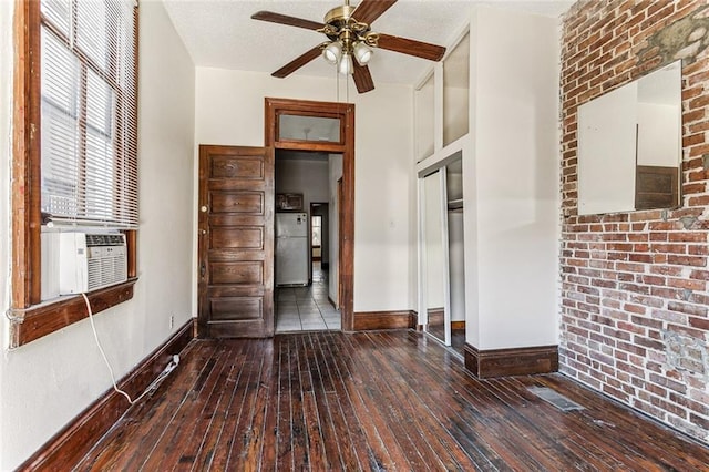 empty room with dark wood-type flooring, cooling unit, a textured ceiling, and ceiling fan