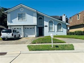 7110 Camberley Dr, New Orleans, LA 70128 - view of front facade with driveway, a garage, and a chimney