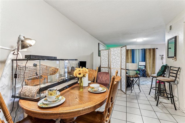 tiled dining room featuring a textured ceiling