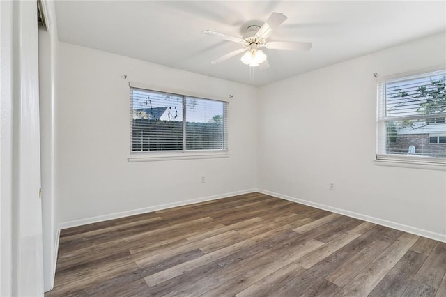 empty room featuring ceiling fan, a healthy amount of sunlight, and dark hardwood / wood-style flooring