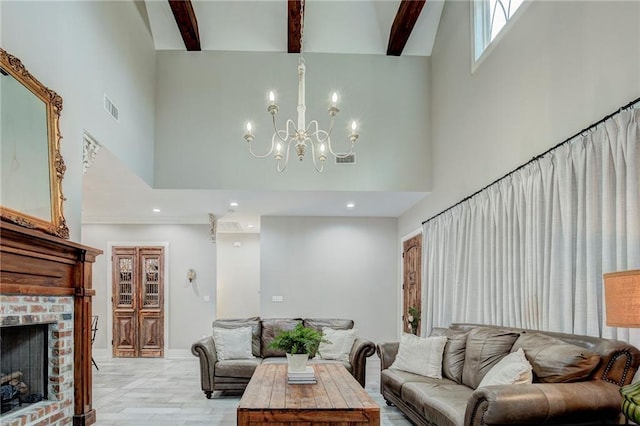 living room with a high ceiling, a notable chandelier, light hardwood / wood-style floors, a brick fireplace, and beamed ceiling