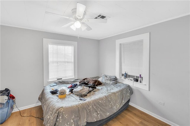 bedroom with wood-type flooring, ornamental molding, and ceiling fan