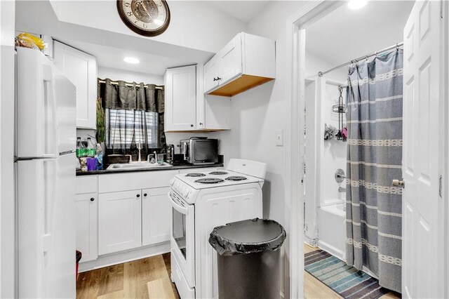 kitchen with white cabinetry, sink, white appliances, and light hardwood / wood-style flooring