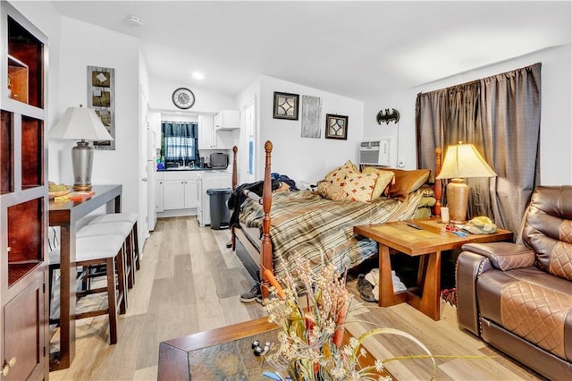 bedroom with lofted ceiling, a wall mounted AC, and light wood-type flooring