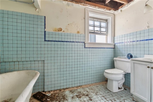 bathroom with tile walls, tile patterned flooring, vanity, a tub to relax in, and toilet