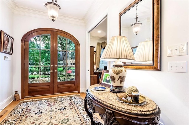 foyer entrance with crown molding, light wood-type flooring, and french doors