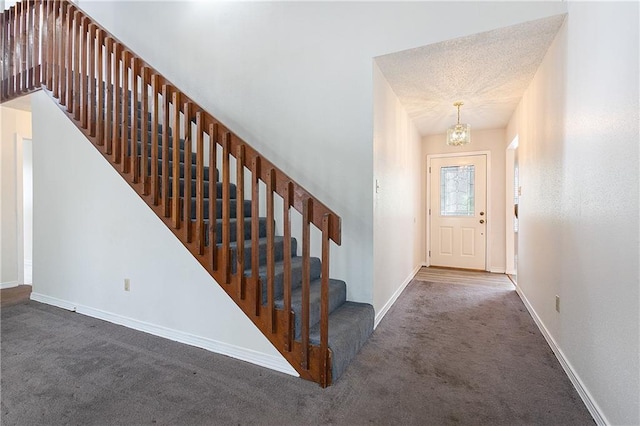 carpeted foyer featuring a textured ceiling and a notable chandelier