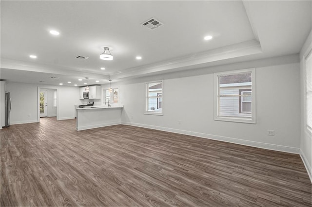 unfurnished living room with dark hardwood / wood-style floors, ornamental molding, and a raised ceiling