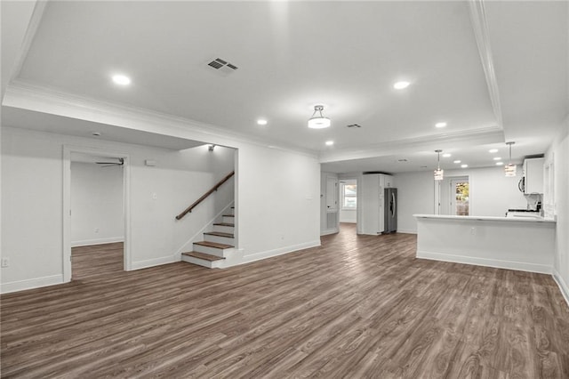 unfurnished living room featuring crown molding, a tray ceiling, and dark hardwood / wood-style flooring