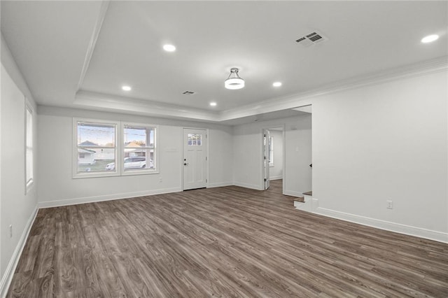 unfurnished living room featuring dark wood-type flooring, crown molding, and a raised ceiling