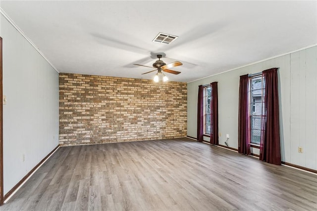 unfurnished room with crown molding, light hardwood / wood-style flooring, ceiling fan, and brick wall