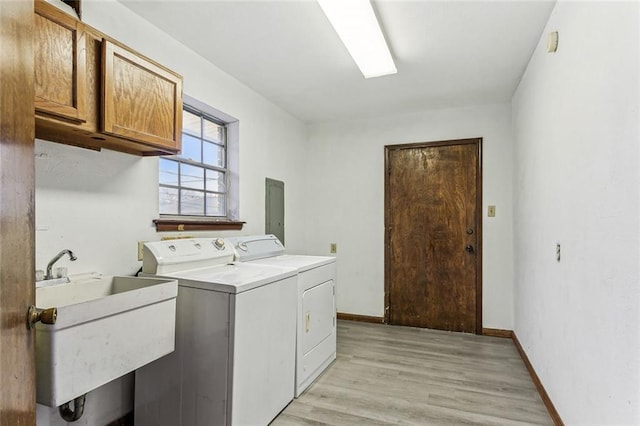 laundry area with cabinets, separate washer and dryer, sink, and light hardwood / wood-style flooring