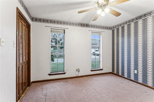 unfurnished room featuring plenty of natural light, carpet floors, and ceiling fan