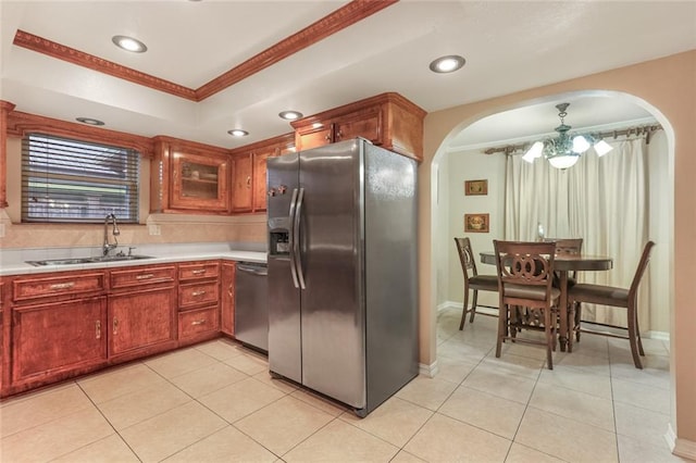 kitchen with ornamental molding, stainless steel appliances, decorative light fixtures, and sink