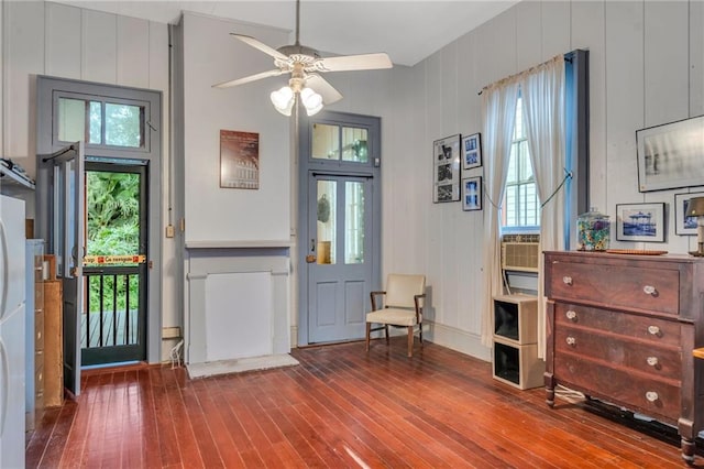 foyer with ceiling fan, wood-type flooring, and wooden walls