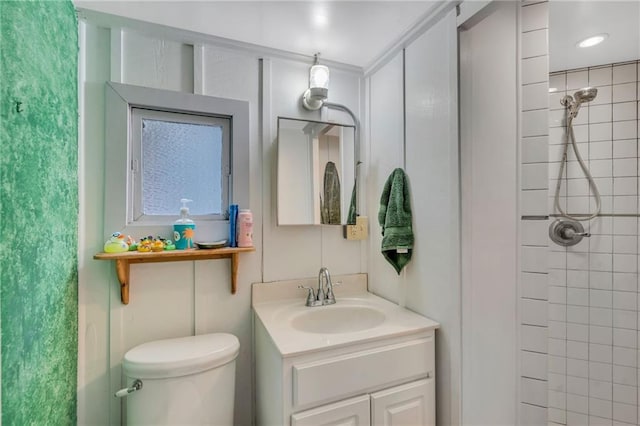 bathroom featuring a tile shower, vanity, and toilet