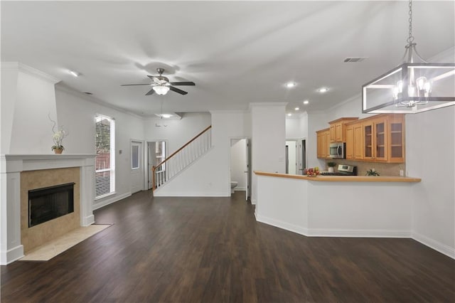 kitchen featuring appliances with stainless steel finishes, dark hardwood / wood-style flooring, hanging light fixtures, ornamental molding, and a high end fireplace