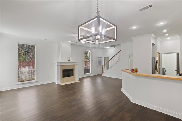 unfurnished living room featuring an inviting chandelier, dark hardwood / wood-style flooring, a fireplace, and ornamental molding