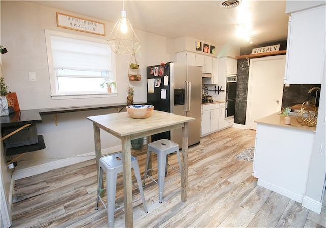 kitchen featuring sink, white cabinets, hanging light fixtures, stainless steel fridge with ice dispenser, and light hardwood / wood-style flooring