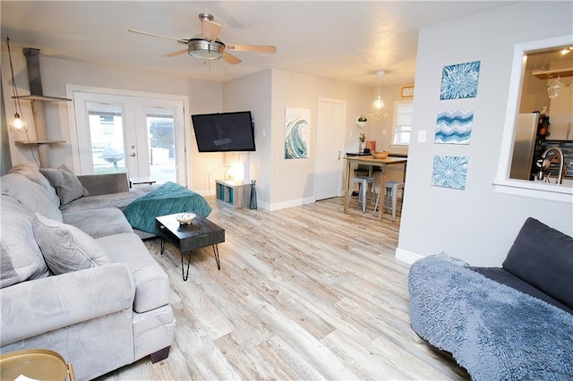 living room featuring sink, light hardwood / wood-style flooring, french doors, and ceiling fan