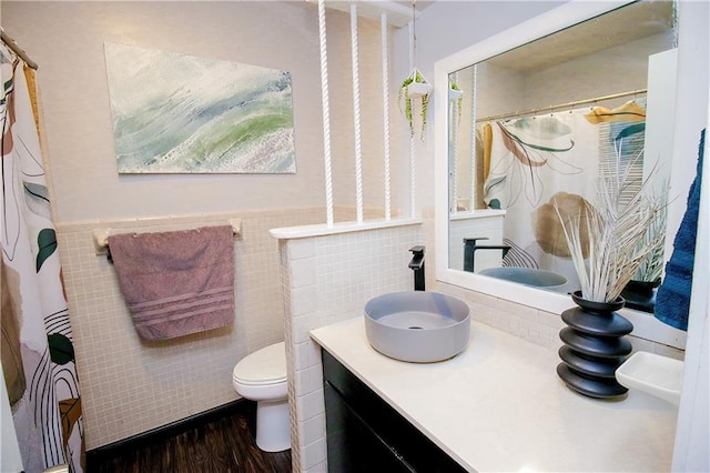 bathroom with wood-type flooring, tile walls, vanity, and toilet