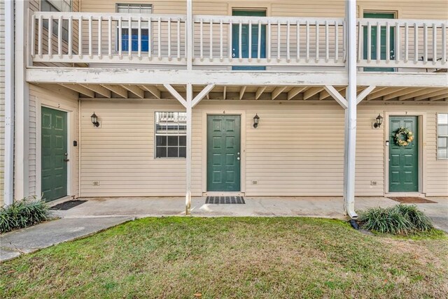 doorway to property with a balcony and a yard