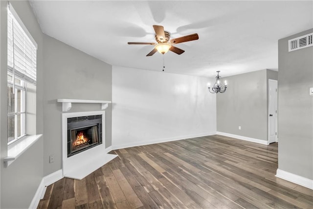 unfurnished living room with dark wood-style floors, a lit fireplace, visible vents, and baseboards