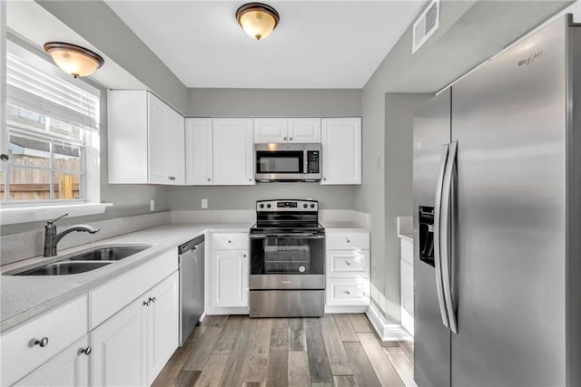 kitchen featuring stainless steel appliances, a sink, visible vents, white cabinetry, and light countertops