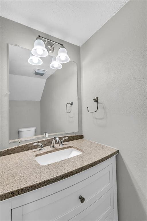 half bathroom with visible vents, vanity, and toilet