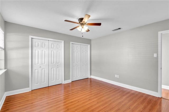 unfurnished bedroom featuring visible vents, baseboards, and wood finished floors