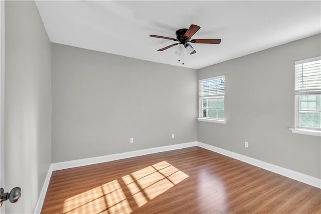 unfurnished room with plenty of natural light, baseboards, and wood finished floors