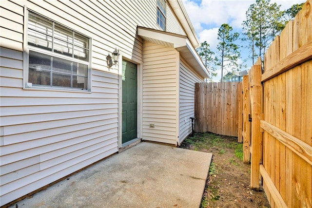 view of exterior entry with a patio area and fence