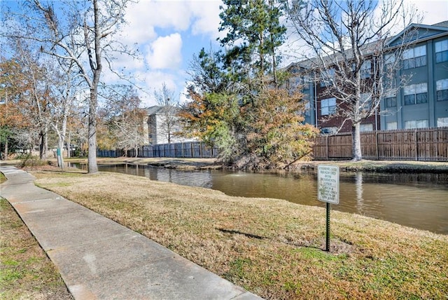 view of home's community featuring a yard, a water view, and fence