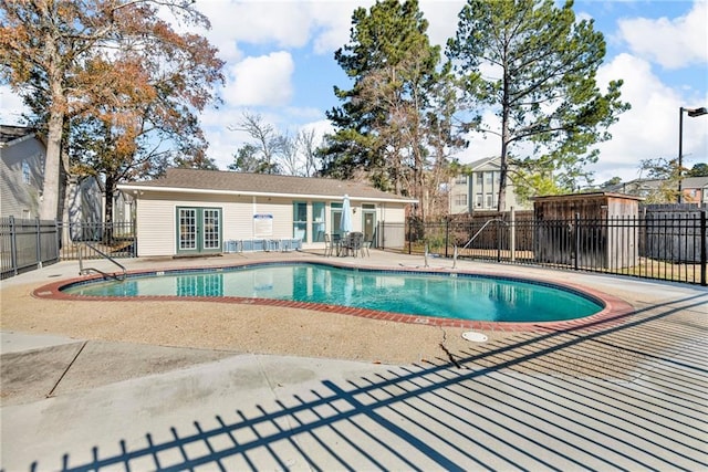 pool with a patio area, fence, and french doors