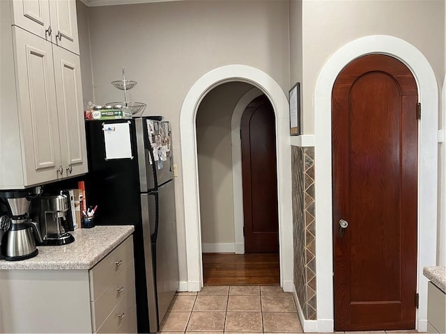 kitchen with stainless steel refrigerator, white cabinets, and light tile patterned flooring