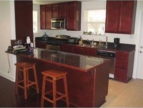 kitchen with stainless steel appliances, sink, a kitchen breakfast bar, and kitchen peninsula