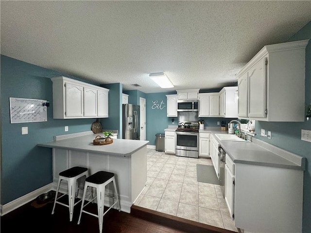 kitchen featuring sink, a breakfast bar area, white cabinets, kitchen peninsula, and stainless steel appliances