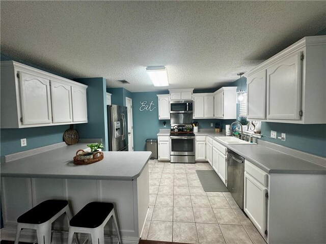 kitchen featuring appliances with stainless steel finishes, pendant lighting, white cabinetry, sink, and kitchen peninsula