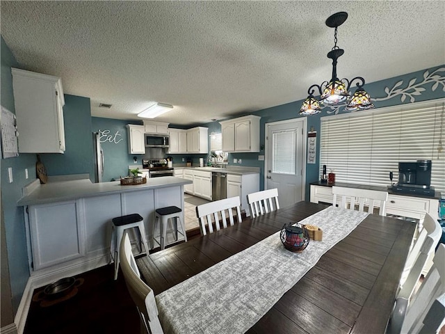 dining room featuring dark hardwood / wood-style floors, sink, a textured ceiling, and a notable chandelier