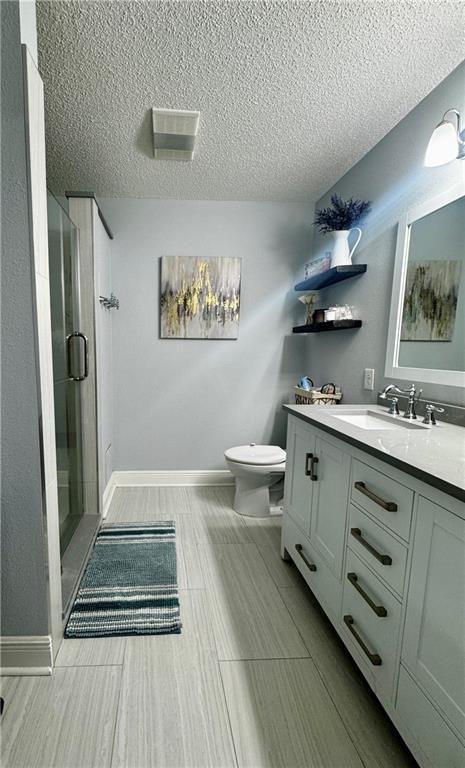 bathroom with walk in shower, vanity, and toilet