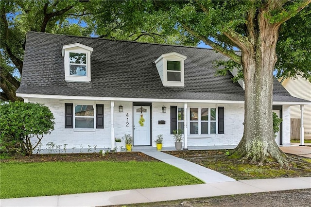 cape cod home featuring a front lawn