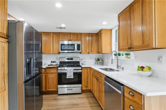 kitchen with stainless steel appliances, sink, and light hardwood / wood-style flooring